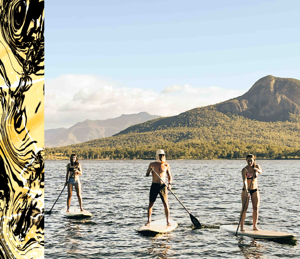 three people SUP'ing on a lake with a mountain behnind